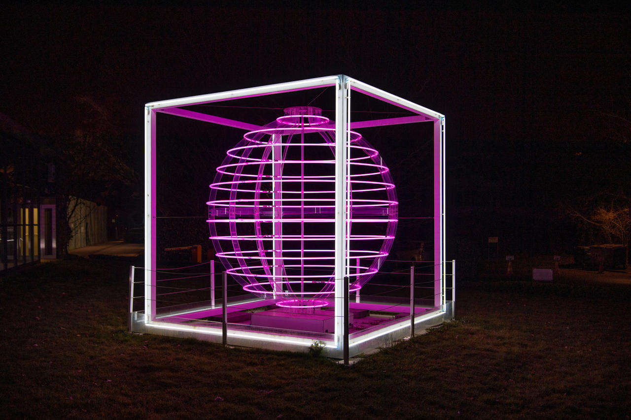 Sculpture lumineuse "Pulsar" de Dara Gallopin (photo de Giorgio Skory pour Commune de Cologny) Vue de l'Oeuvre (sphère lumineuse en tubes néon de couleur rose-violette dans un cadre cubique blanc)
