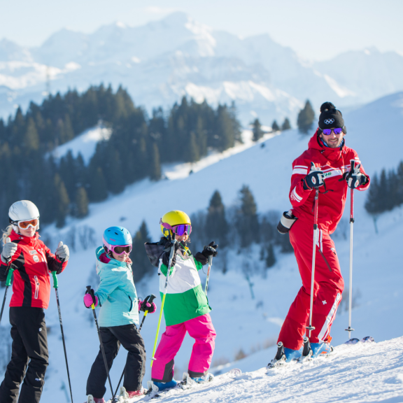 Moniteur de ski et 3 enfants dans un paysage enneigé