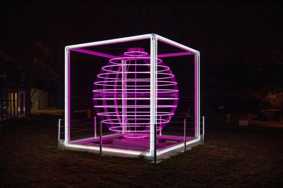 Sculpture lumineuse "Pulsar" de Dara Gallopin (photo de Giorgio Skory pour Commune de Cologny) Vue de l'Oeuvre (sphère lumineuse en tubes néon de couleur rose-violette dans un cadre cubique blanc)